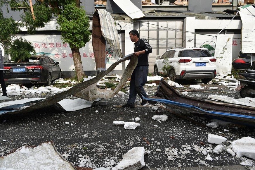 epa09200733 A villager clears the road of debris in the aftermath of a tornado in Shengze township, Suzhou, Jiangsu province, China, 15 May 2021. At least one person was killed and over 20 were injure ...