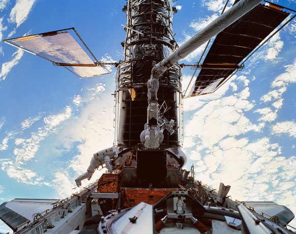 STS103-501-026 19 a 27 de dezembro de 1999 --- Os astronautas C. Michael Foale, à esquerda, e Claude Nicollier no braço robótico do Discovery instalam um Sensor de Orientação Fina FGS em um compartimento de proteção no Ônibus Espacial ...