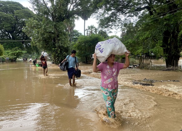 epa11601503 People carry their belonging as they wade through flood waters in Pyinmana, Naypyidaw, Myanmar, 13 September 2024. Heavy rains triggered by Typhoon Yagi have caused severe flooding in part ...