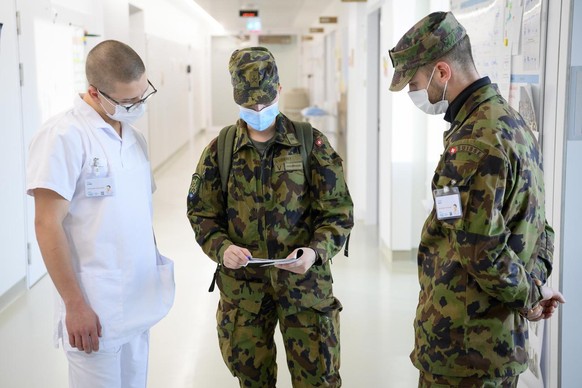 Des soldats suisses discutent dans un couloir des Hôpitaux universitaires de Genève en novembre 2020.