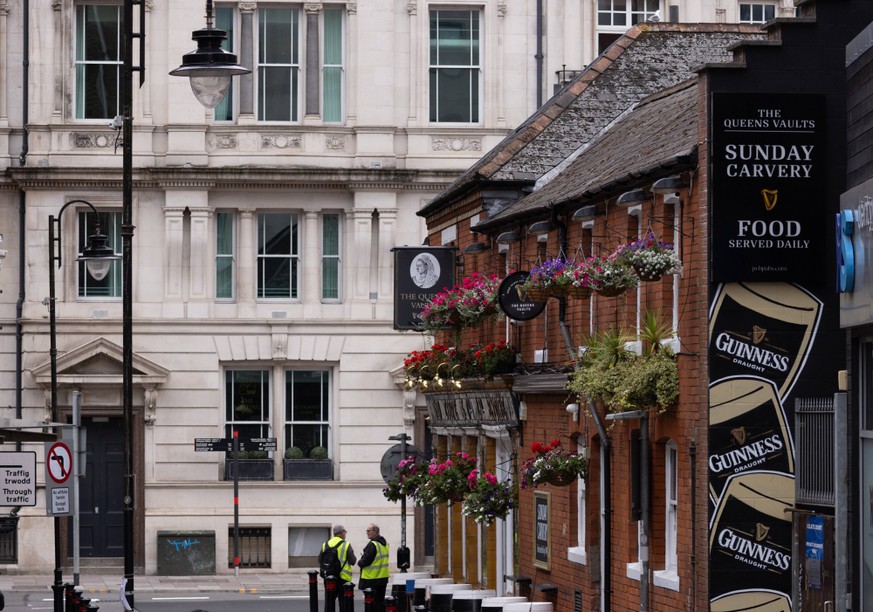 CARDIFF, UK - AUGUST 8, 2025 - Der Queens Vaults Pub in Cardiff, Wales, zeigt Sicherheitskr臟te, die den Zugang kontrollieren CARDIFF, UK - AUGUST 8, 2025 - Two security guards controlling access to Th ...