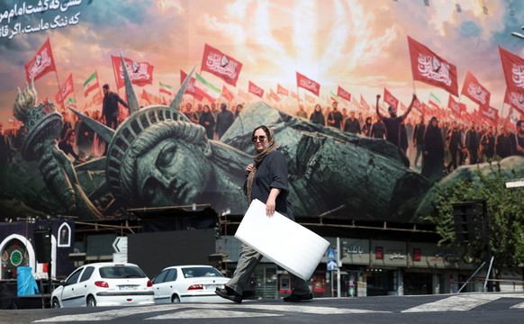Le régime iranien utilise la guerre à des fins de propagande. Une Iranienne passe devant un panneau publicitaire anti-américain dans le centre de Téhéran.