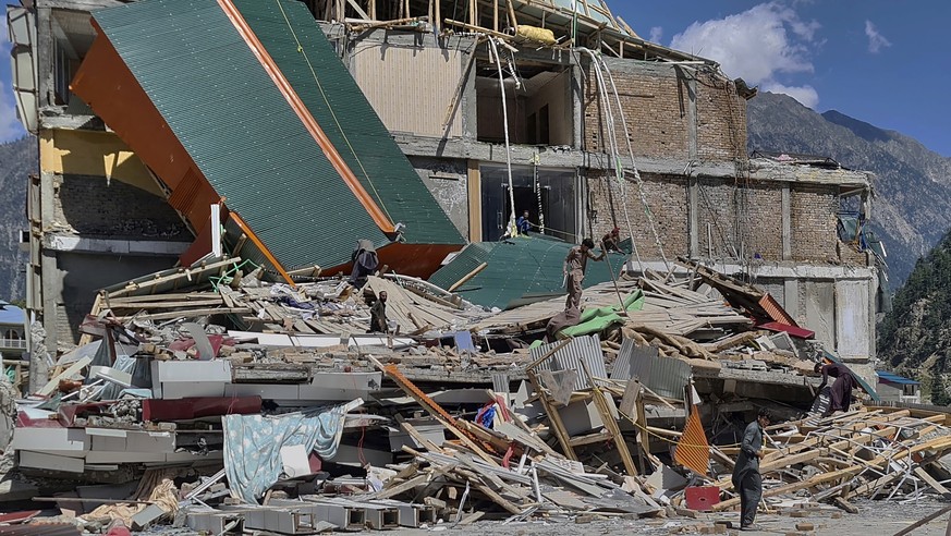 People salvage usable items from a damaged hotel building caused by floodwaters in the village of Kalam in the Swat Valley, Pakistan, Tuesday, Aug. 30, 2022. Disaster officials say nearly a half milli ...