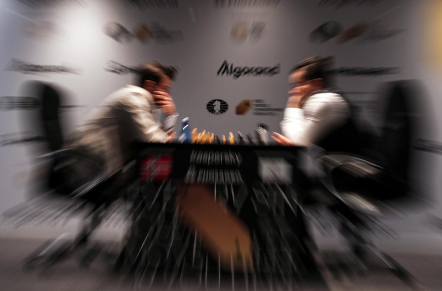 epa09606836 Defending Champion Magnus Carlsen of Norway (L) plays against Ian Nepomniachtchi of Russia during the second round of FIDE World Chess Championship during the EXPO 2020 Dubai in Dubai, Uni ...