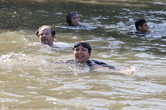 epa11483082 Paris Mayor Anne Hidalgo (C) swims in the Seine to demonstrate that the river is clean enough to host the outdoor swimming events at Paris 2024 Olympic Games, in Paris, France, 17 July 202 ...