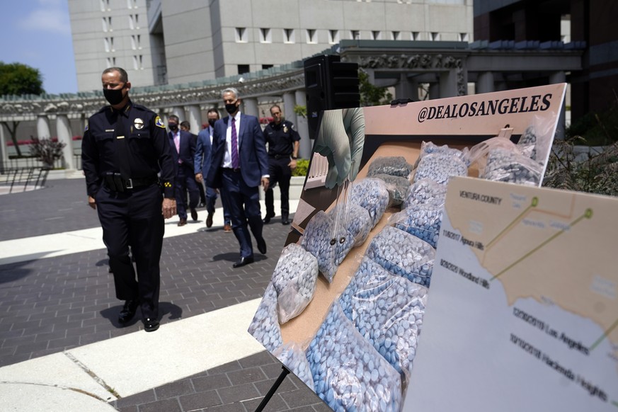 Officials walk past images of illegal drugs outside the Edward R. Roybal Federal Building, Thursday, May 13, 2021, in Los Angeles. Federal authorities say they have arrested at least 10 suspected drug ...