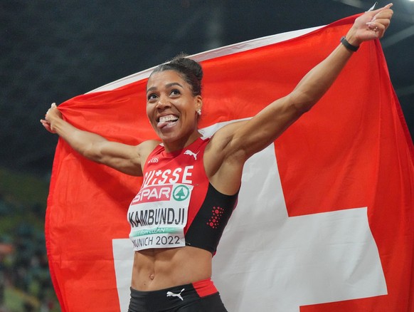 19.08.2022, Bayern, München: Leichtathletik: Europameisterschaft, Olympiastadion, Frauen, 200 Meter, Finale, Mujinga Kambundji (Schweiz) gewinnt das Rennen und jubelt mit der Landesfahne. Foto: Soeren ...