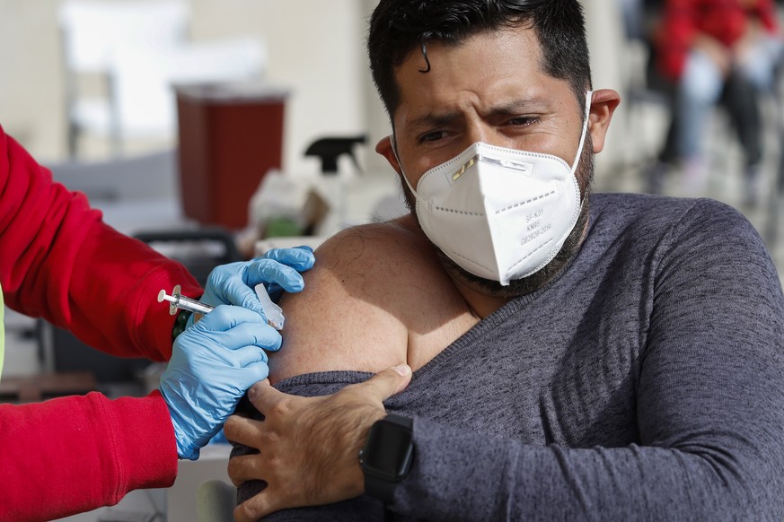 epa09653035 Iver Casillas receives a dose of the Moderna COVID-19 vaccine at a vaccination site at Lincoln Park Recreation Center in Los Angeles, California, USA, 21 December 2021. The Omicron variant ...