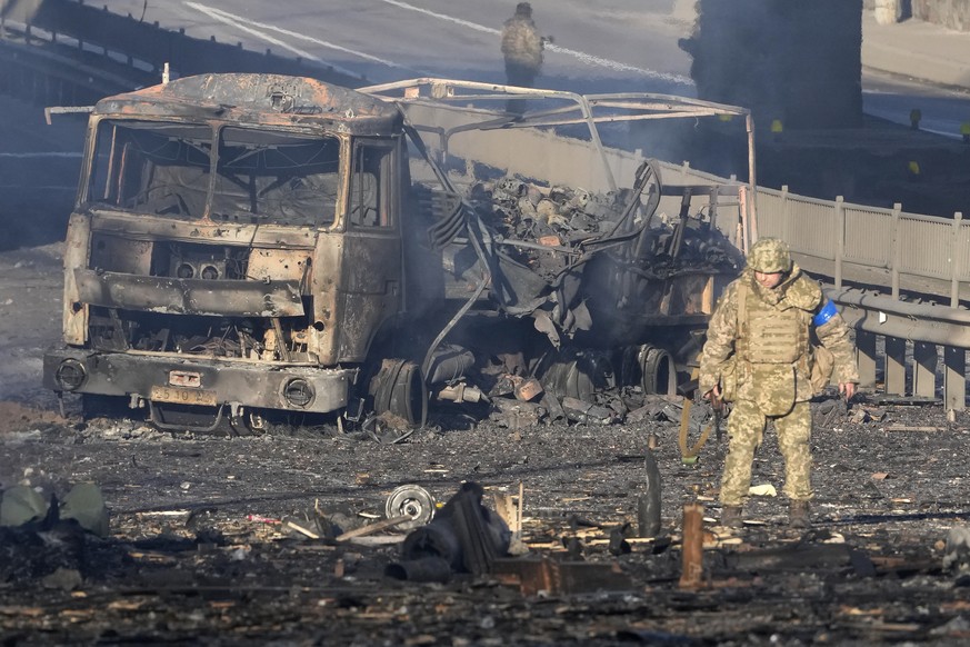 A Ukrainian soldier walks past debris of a burning military truck, on a street in Kyiv, Ukraine, Saturday, Feb. 26, 2022. Russian troops stormed toward Ukraine&#039;s capital Saturday, and street figh ...