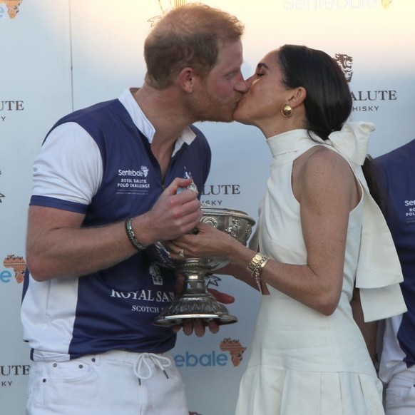 The Duchess of Sussex presents the trophy to her husband, the Duke of Sussex after his team the Royal Salute Sentebale Team defeated the Grand Champions Team, in the Royal Salute Polo Challenge, to be ...