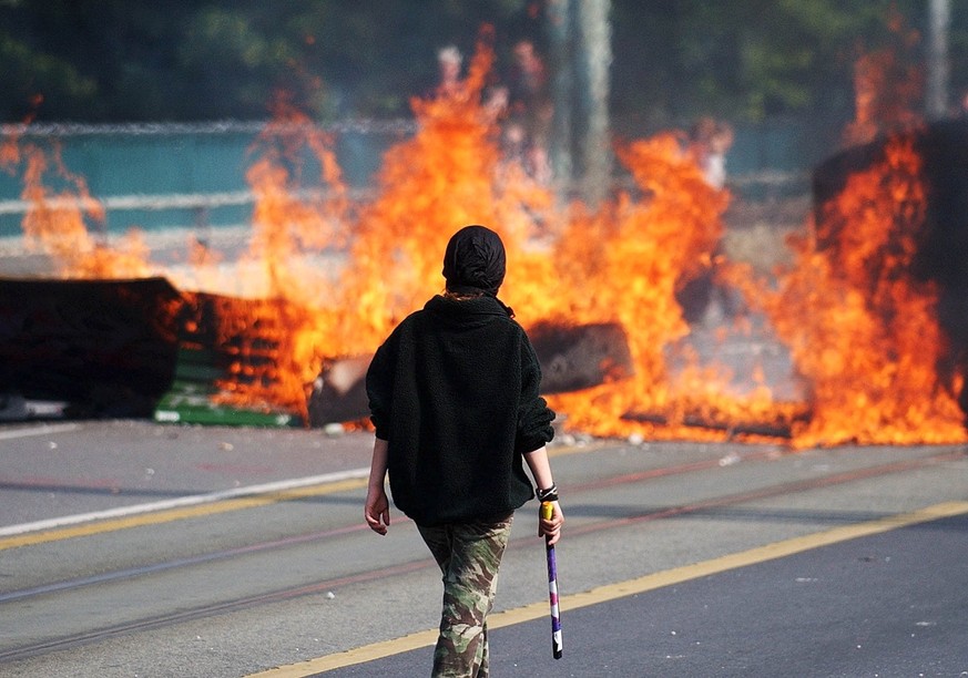 A demonstrator walks in front of a buring barricade on the bridge Coulouvriniere in Geneva, Switzerland, Sunday, June 1, 2003. Several hundred anti G8 demonstrators have blocked the bridges in Geneva ...