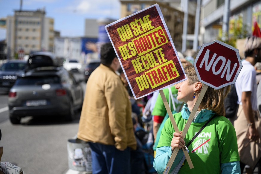 Des personnes manifestent contre les projets d&#039;extensions d&#039;autoroutes en montrant leurs pancartes aux voitures ce samedi 5 octobre 2024 a Lausanne. Le 24 novembre prochain, la population se ...