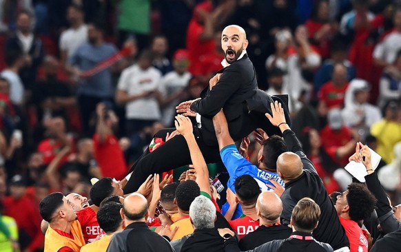 epa10359700 Morocco&#039;s head coach Walid Regragui (up) and his players celebrate after winning the FIFA World Cup 2022 quarter final soccer match between Morocco and Portugal at Al Thumama Stadium  ...