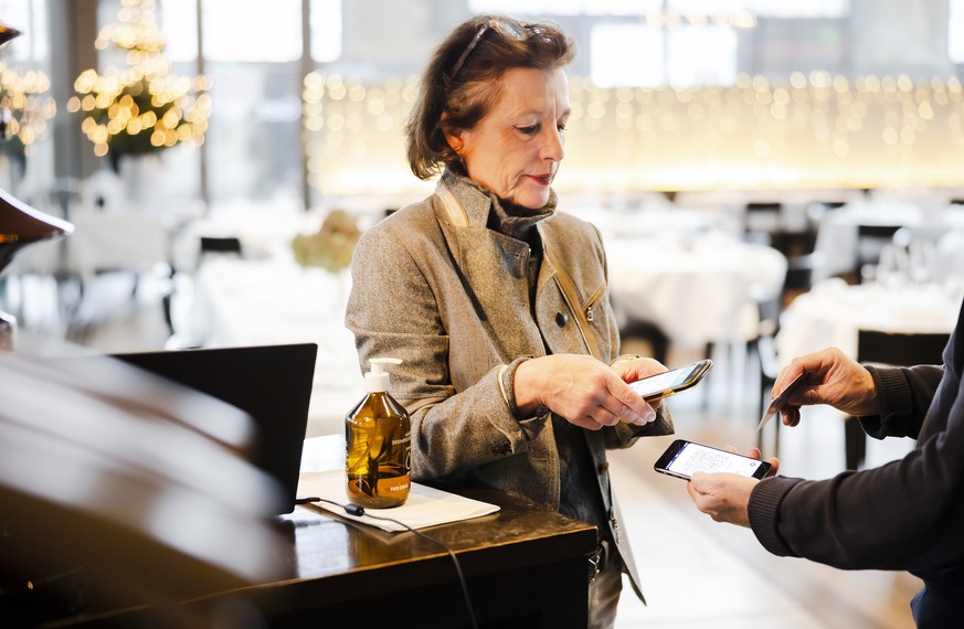 Restaurant Inhaberin Claudine Brunner kontrolliert ein Covid-Zertifikat im Restaurant LaSalle wo die 2G-Regel gilt und nur Gaeste die gegen das Coronavirus Covid-19 geimpft oder genesen sind Zutritt h ...