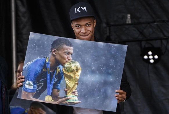 epa07100188 France&#039;s soccer player Kylian Mbappe (R) poses with a picture of him kissing the Jules Rimet trophy during his first visit to the Leo Lagrange stadium in his childhood city, since Fra ...