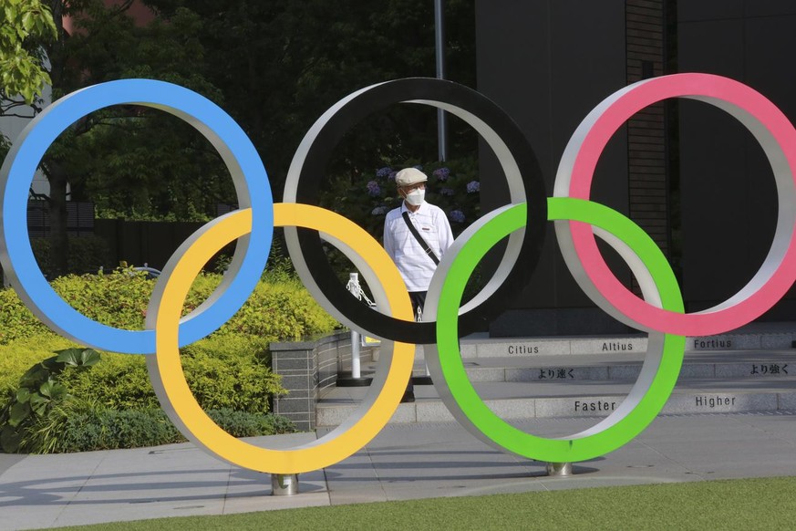 A man walks past the Olympic rings in Tokyo, Monday, June 7, 2021. (AP Photo/Koji Sasahara)