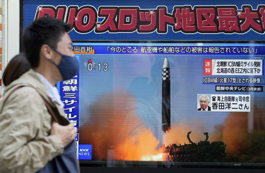 epa10311935 Pedestrians walk past a street television showing news of North Korea firing a ballistic missile on a street in Tokyo, Japan, 18 November 2022. North Korea launched what is believed to be  ...