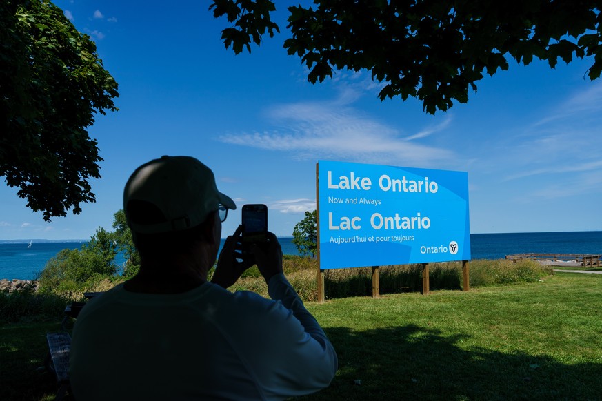 A person takes a picture of the newly unveiled sign for Lake Ontario at Fifty Point Conservation Area in Grimsby, Ontario, Canada, on Saturday, Aug. 29, 2026. (Keito Newman/The Canadian Press via AP)
 ...