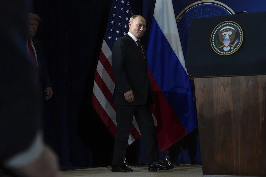 Le dirigeant du Kremlin Vladimir Poutine (au centre) se rendant à la conférence de presse en Alaska. Derrière lui, dans l&#039;ombre: le président américain Donald Trump.