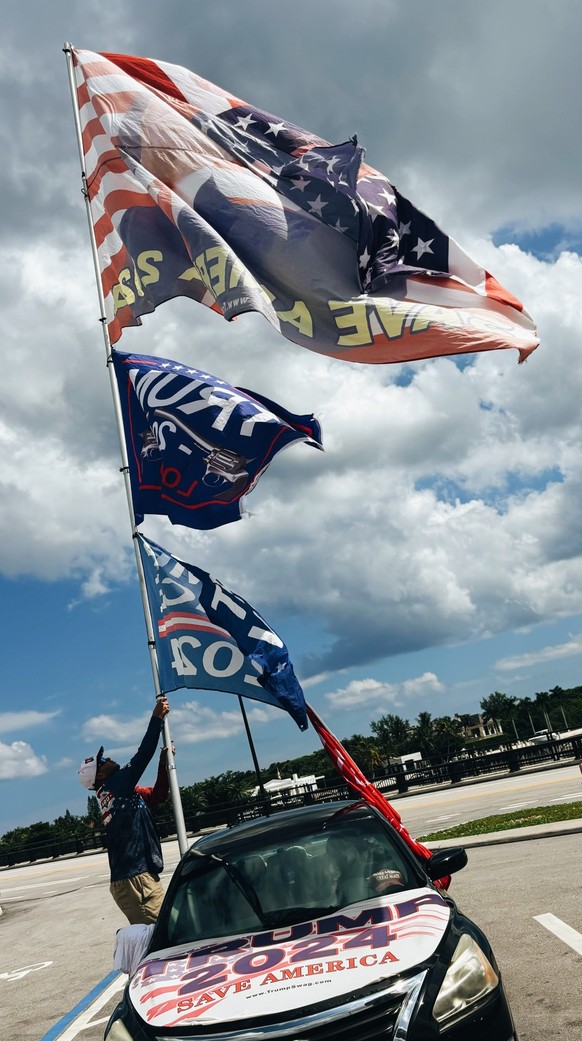 Jestin Nelvarez, supporter de Donald Trump, hisse un drapeau sur le parking à promitié de Mar-a-Lago, en Floride.