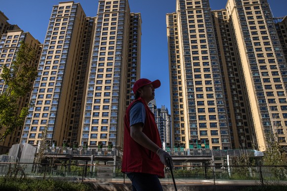 epa09481142 A woman walks at Evergrande city plaza, next to its apartment buildings, in Beijing, China, 22 September 2021. China&#039;s real estate developer Evergrande Group said it would pay schedul ...