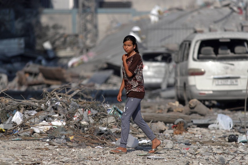 231011 -- GAZA, Oct. 11, 2023 -- A girl walks past buildings destroyed in Israeli airstrikes in Gaza City, on Oct. 11, 2023. The Palestinian Islamic Resistance Movement Hamas on Saturday launched a su ...