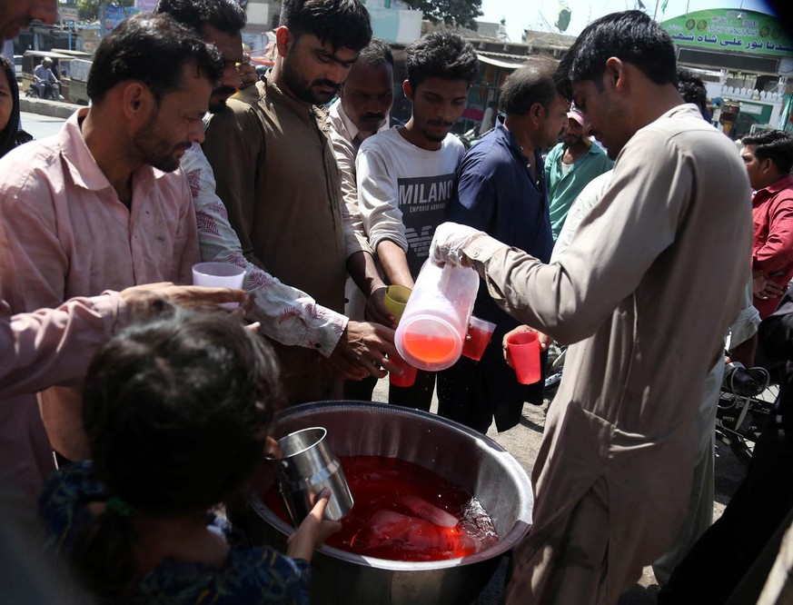 Des gens boivent du jus gratuit sur le bord de la route, pour combattre la chaleur à Karachi, au Pakistan, le 15 mars 2022.
