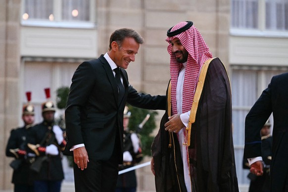 France's President Emmanuel Macron (L) welcomes Saudi Arabia's Crown Prince Mohammed bin Salman as he arrives for a State diner in his honour at the Elysee Palace in Paris on August 24, 2026 ...