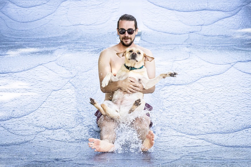 epa13251746 Fabian and his dog Meyla are on a water slide at the Toess public outdoor pool in Winterthur, Switzerland, 20 September 2026. The facility opens its chlorine-free pools to dogs for a one-d ...
