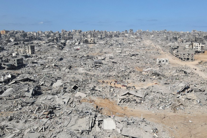 In this aerial view, People walk amid the destruction in Gaza City in the northern Gaza Strip on October 11, 2025, a day after a ceasefire took effect. Israel declared a ceasefire in Gaza and began to ...