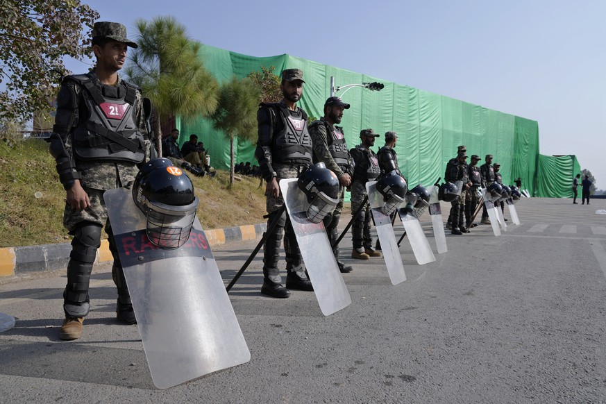 Paramilitary soldiers stand guard with riot gears at a road barricaded with shipping containers ahead of a planned rally by supporters of imprisoned former Prime Minister Imran Khan&#039;s Pakistan Te ...