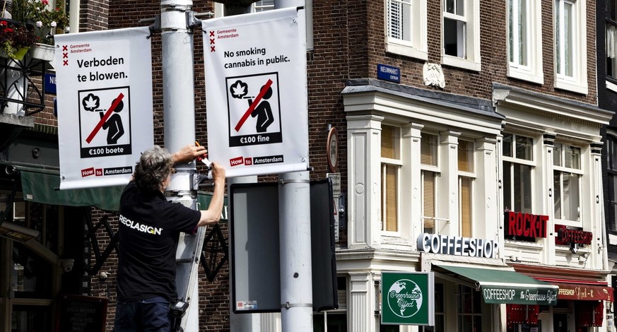 epa10647647 An employee of the municipality places a prohibition sign on the Nieuwmarkt in Amsterdam, the Netherlands, 23 May 2023. From 25 May it is forbidden to smoke weed in the old city center of  ...