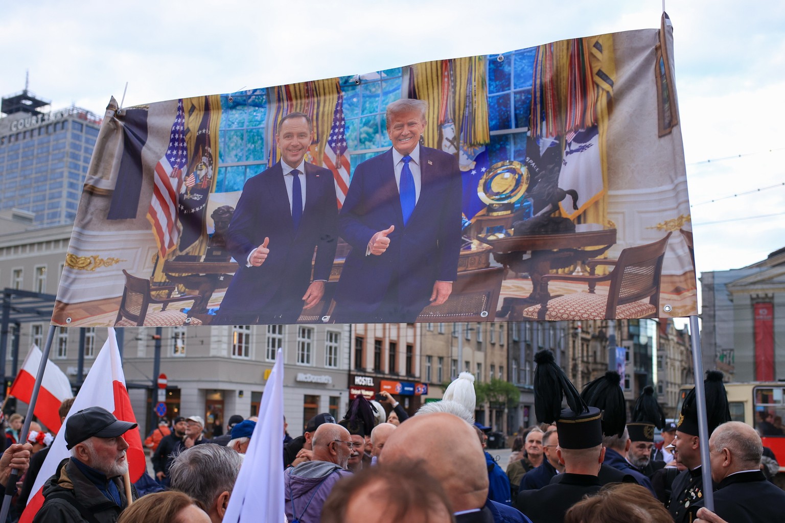 epa12143932 Supporters of the 2025 presidential election candidate Karol Nawrocki hold banner with a picture from a meeting between US President Donald Trump and Nawrocki during an election campaign e ...