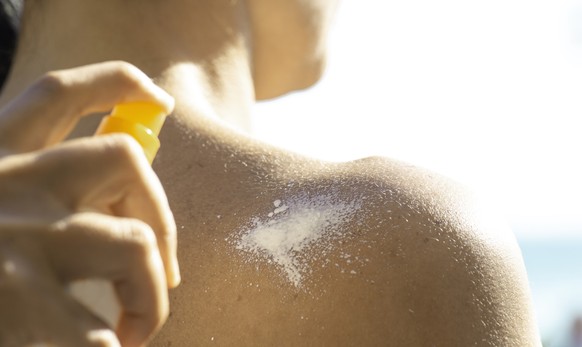 Mann wird eingecremt mit Sonnencreme-Spray
