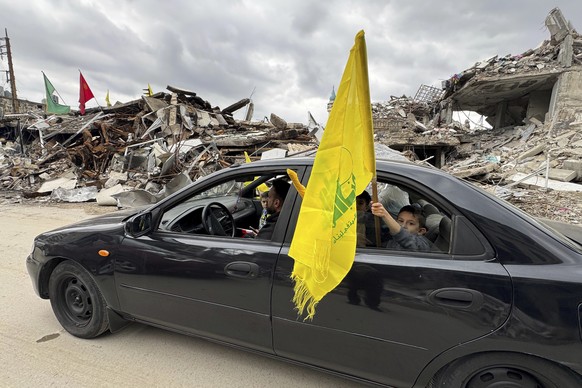 A boy holds a Hezbollah&#039;s flag, as displaced residents return to Nabatiyeh, southern Lebanon, Thursday, Nov. 28, 2024 following a ceasefire between Israel and Hezbollah that went into effect on W ...