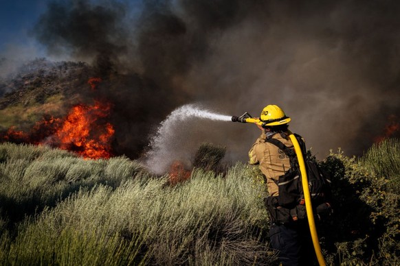 Gorman, CA - June 16: On Orwin road fire crews battle a hot spot at the Gorman Brush Fire in northern Los Angeles County on Sunday, June 16, 2024 in Gorman, CA. (Jason Armond / Los Angeles Times via G ...