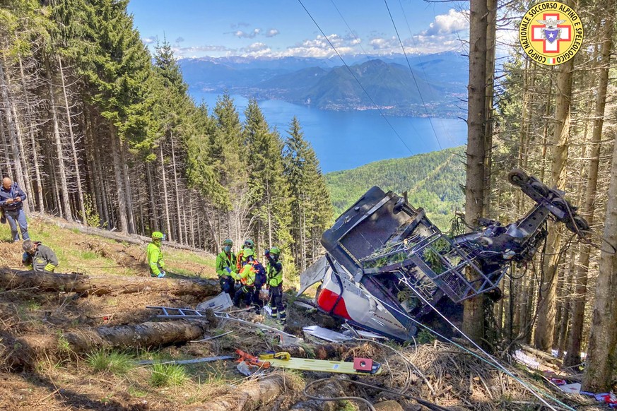 Rescuers work by the wreckage of a cable car after it collapsed near the summit of the Stresa-Mottarone line in the Piedmont region, northern Italy, Sunday, May 23, 2021. A mountaintop cable car plung ...