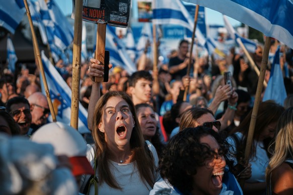 People react as they gather to watch a live broadcast of Israeli hostages released from Gaza at a plaza known as hostages square in Tel Aviv, Israel, Monday, Oct. 13, 2025. The release took place as p ...