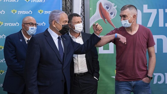 Israeli Prime Minister Benjamin Netanyahu, second left, visits the Leumit Health Care Services vaccination facility and bumps elbows with Theodor Salzen, the 4 millionth person in Israel to be vaccina ...