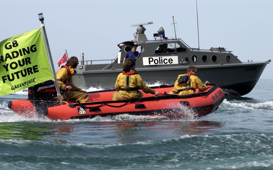Greenpeace activist in an inflatable are being stopped by a police boat, Monday, June 2, 2003 on Lake Geneva, on their way to Evian, France. The crew of three inflatables which were flying banners wic ...