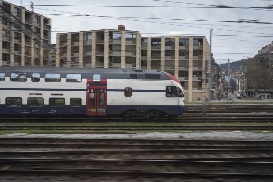 Ein SBB-Zug faehrt in Richtung Zuerich Hauptbahnhof und passiert die Wohnhaeuser Gleis Tribuene der SBB, fotografiert am Dienstag, 10. Dezember 2024 bei Zuerich. (KEYSTONE/Gaetan Bally)