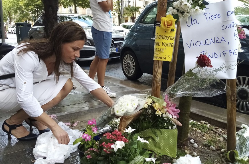 FILE - A woman places a bouquet of flowers where Nigerian street vendor Alika Ogorchukwu was murdered, in Civitanova Marche, Italy, Saturday, July 30, 2022. A judge in Italy on Monday ordered an Itali ...