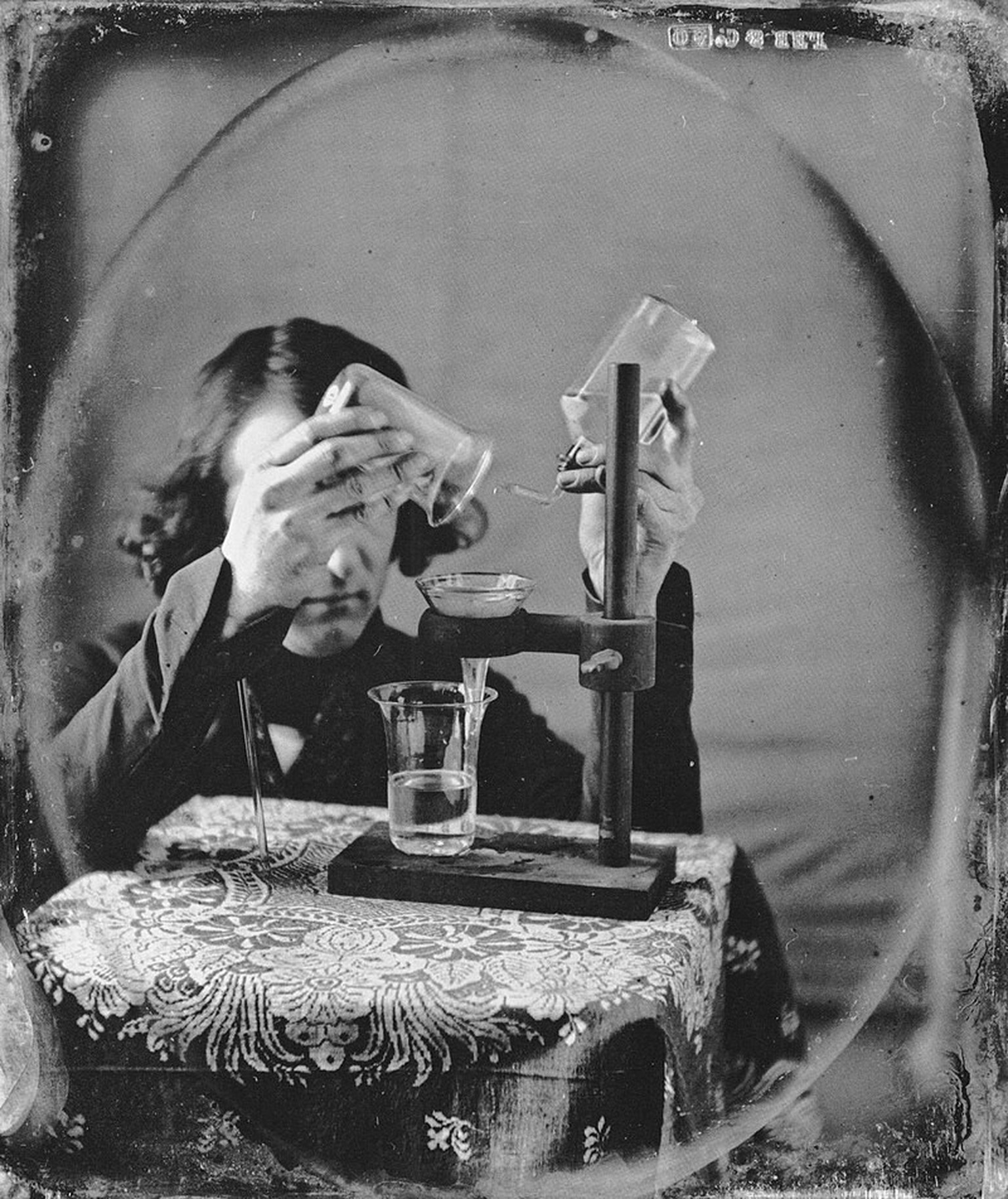 Robert Cornelius bei einem chemischen Experiment, 1843. Ein Glasstab stützt seinen rechten Arm, den er sonst nicht während der gesamten Belichtungszeit hätte ruhig halten können.