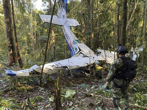 In this photo released by Colombia&#039;s Armed Forces Press Office, a soldier stands in front of the wreckage of a Cessna C206, Thursday, May 18, 2023, that crashed in the jungle of Solano in the Caq ...