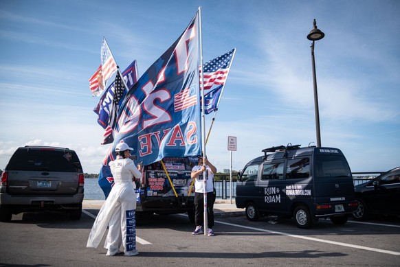 FLORIDA, UNITED STATES - MARCH 5: Supporter of Donald Trump, Binh Vo, and his wife wait near to the Mar-A-Lago Trump Residence with flags for the Super Tuesday Results in Florida, United States on Mar ...