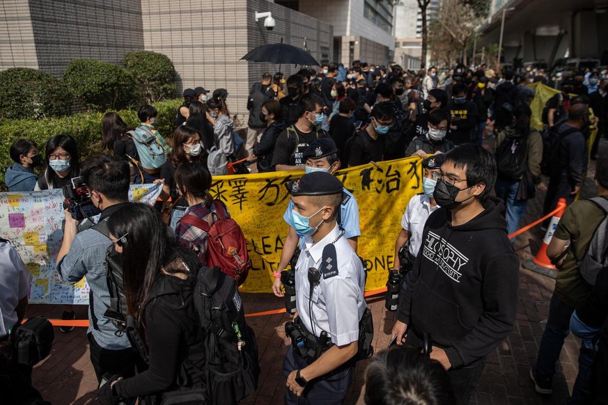 epa09044112 Pro-democracy activists hold banners in support of arrested fellow activists outside the West Kowloon Court in Hong Kong, China, 01 March 2021. Police have charged 47 pro-democracy activis ...