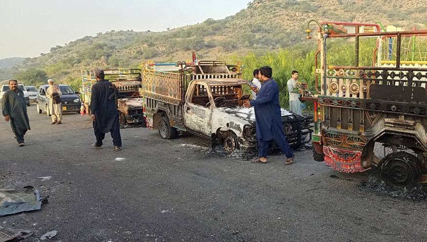 People look burnt vehicles, torched by gunmen after killing passengers, at a highway in Musakhail, a district in Baluchistan province in southwestern Pakistan, Monday, Aug. 26, 2024. (AP Photo/Rahmat  ...