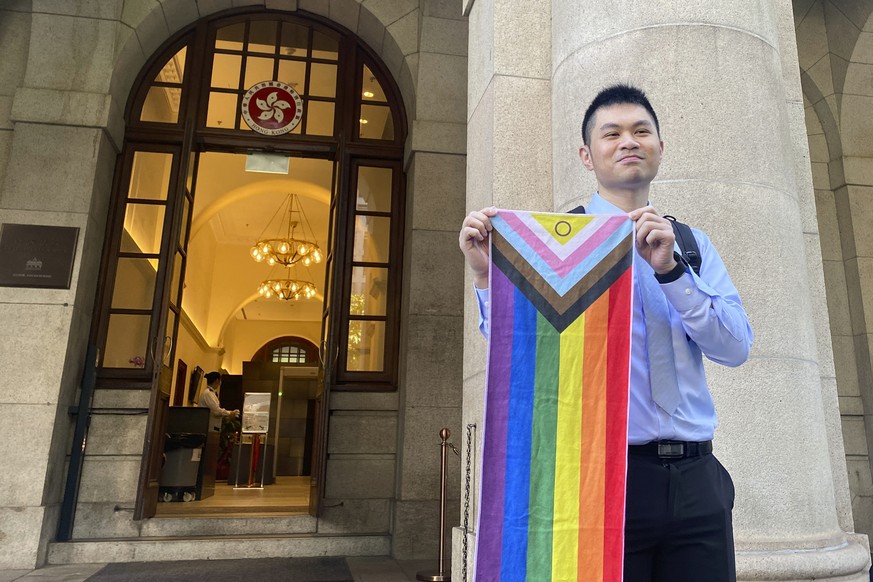 Nick Infinger, who won a years-long legal battle over the differential treatment facing same-sex couples, holds up a rainbow banner after speaking to media members outside Hong Kong?s top court on Tue ...