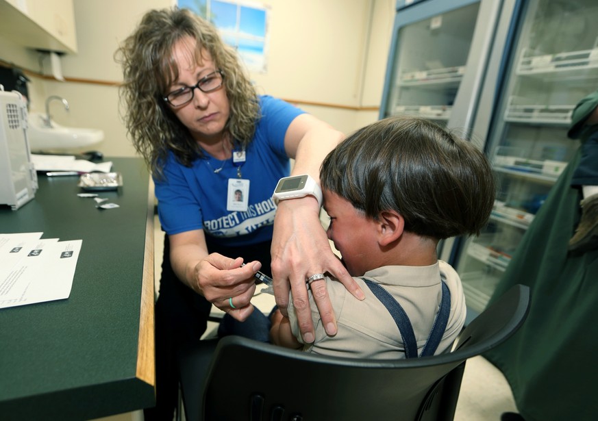 Un petit garçon qui se fait vacciner contre la rougeole par une infirmière.