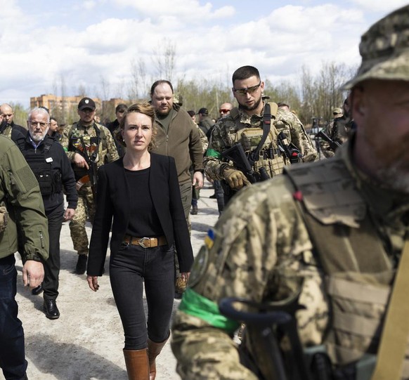 Irene Kaelin, President of the Swiss National Assembly, center, surrounded by members of the Ukrainian military, leaves the Hostomel airfield near Kiev, Ukraine, which was destroyed by Russian invader ...